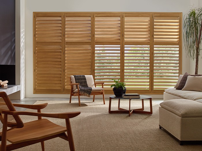 A living room with windows featuring Heritance® Hardwood Shutters Color: Palomino